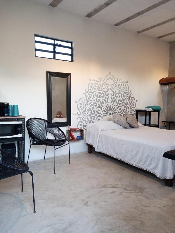 a bedroom with a bed and a mirror and a chair at Casa Ha Hostal in Mérida