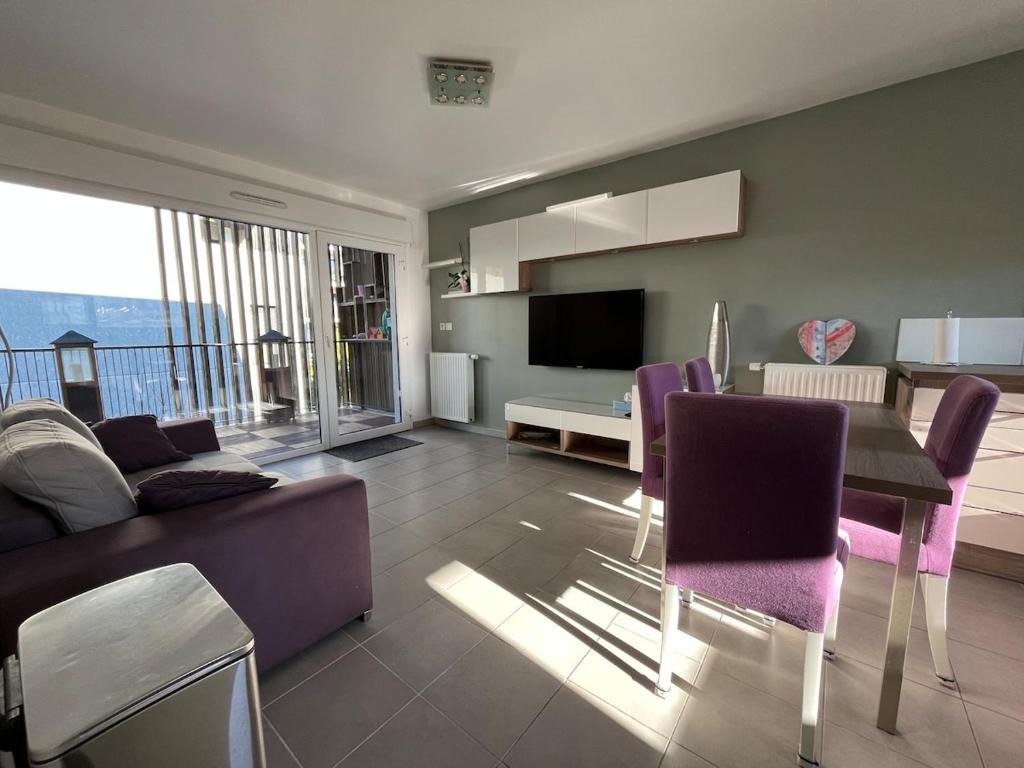 - un salon avec un canapé et une table avec des chaises violettes dans l'établissement 3 pièces central au pied de la promenade du paillon, à Nice