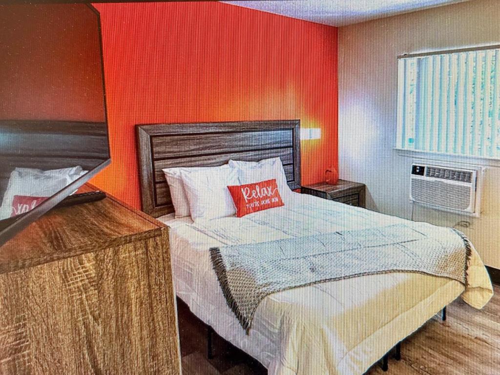 een slaapkamer met een bed met een oranje muur bij Siegel Select Orange Park in Orange Park