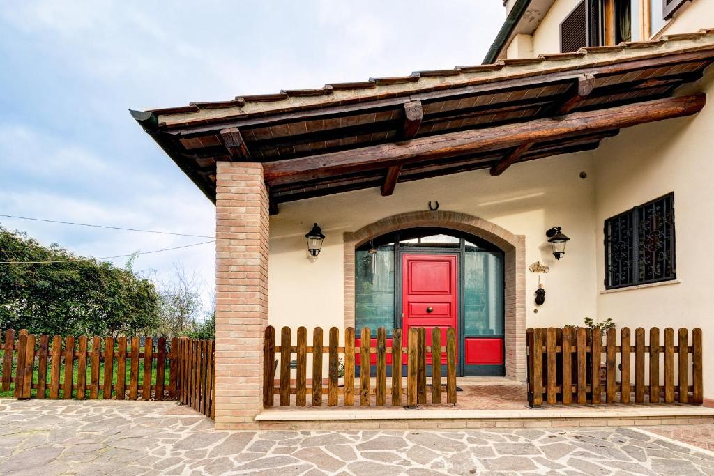 a red door on a house with a fence at Back Home in Pienza