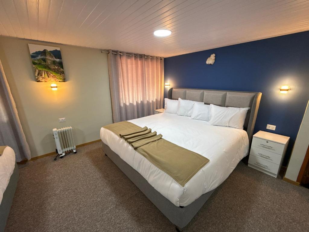 a bedroom with a large bed and a blue wall at Andenes del Inca Hotel in Ollantaytambo