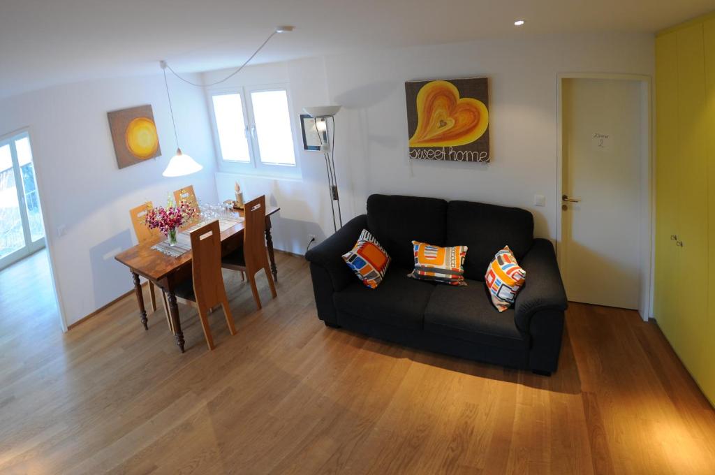 a living room with a black couch and a table at Bed and Breakfast Wegmann in Andelfingen