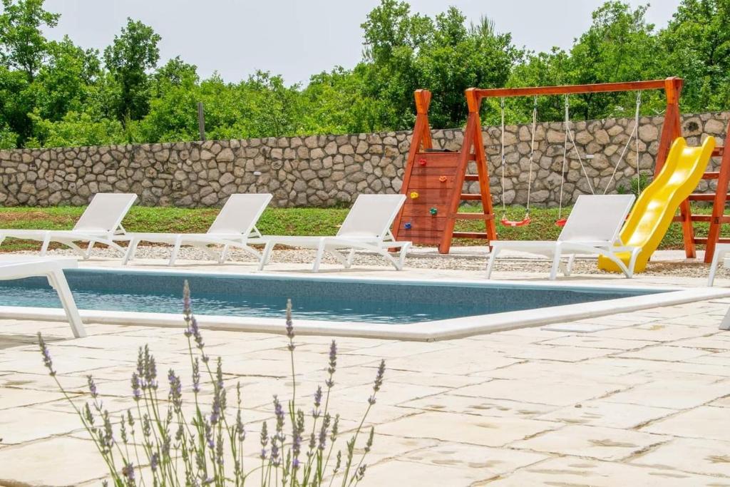 a pool with white chairs and a slide at Family friendly house with a swimming pool Posedarje, Novigrad - 23578 in Posedarje