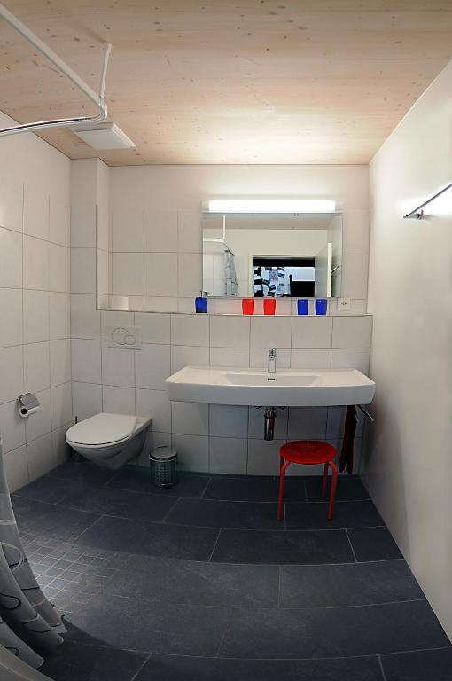 a bathroom with a sink and a toilet and a red stool at Bed and Breakfast Wegmann in Andelfingen