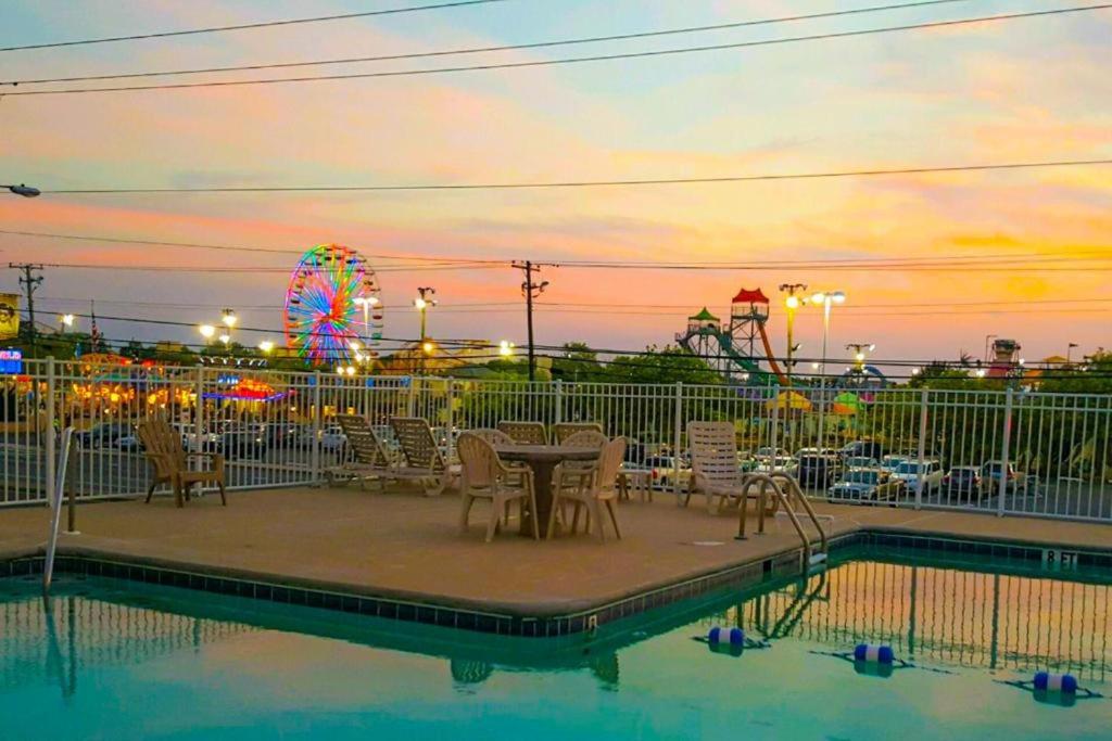大洋城Stunning Studio with community pool just steps to Beach and Boardwalk!的嘉年华旁边的一个带桌椅的游泳池