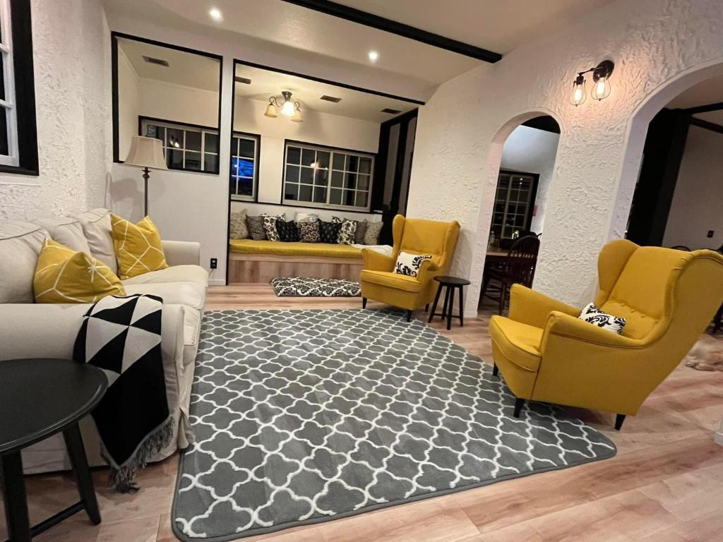 a living room with yellow chairs and a rug at The Bunkhouse Hakuba by Mr T in Hakuba