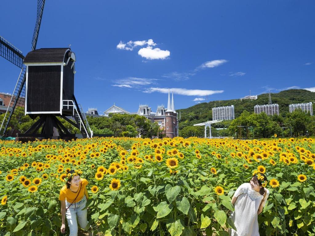 two people walking in a field of sunflowers at Hotel Amsterdam Huis Ten Bosch in Sasebo