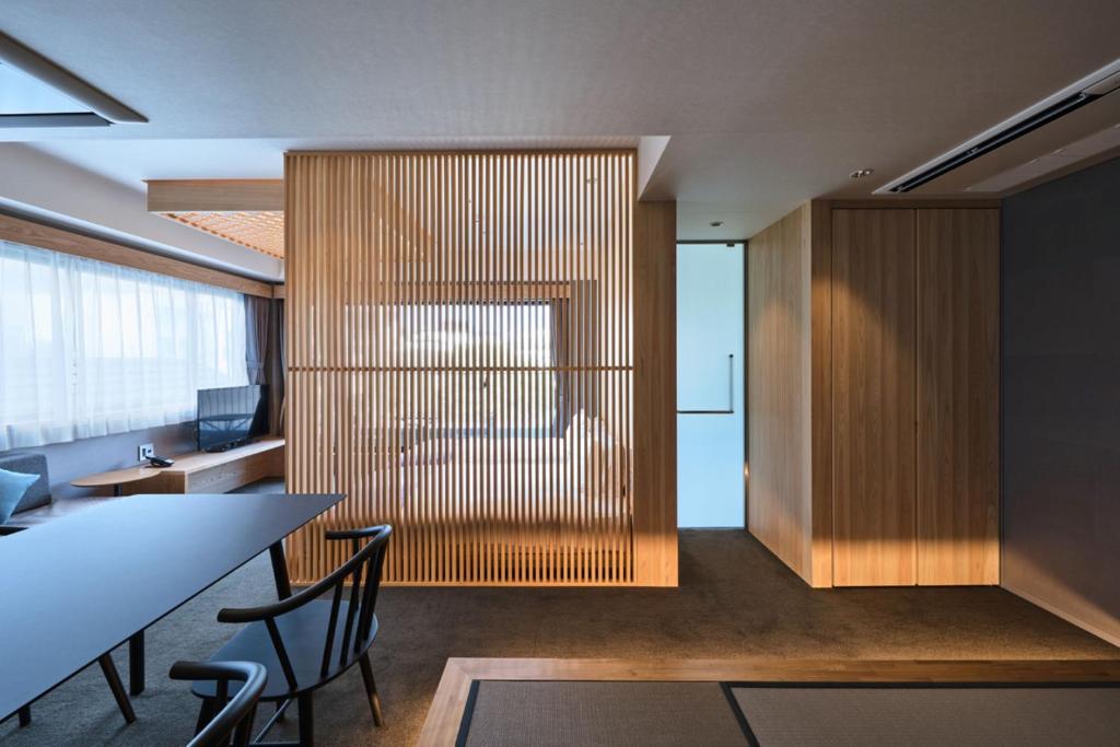 a room with a table and chairs and a wall with wood at Minn Nijo-jo in Kyoto