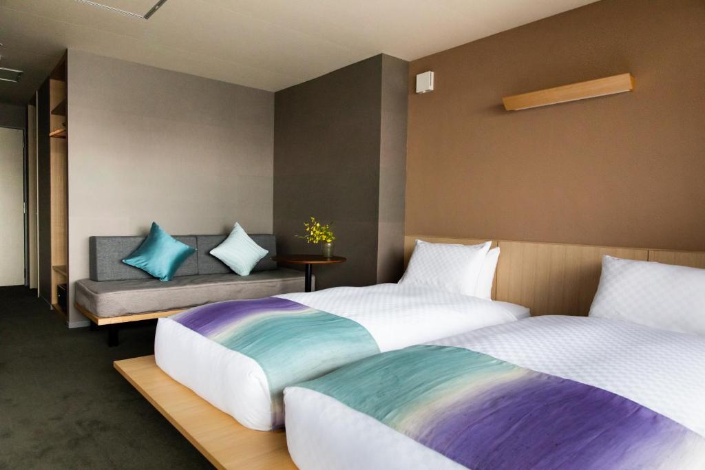 a bedroom with two beds and a bench at Minn Nijo-jo in Kyoto
