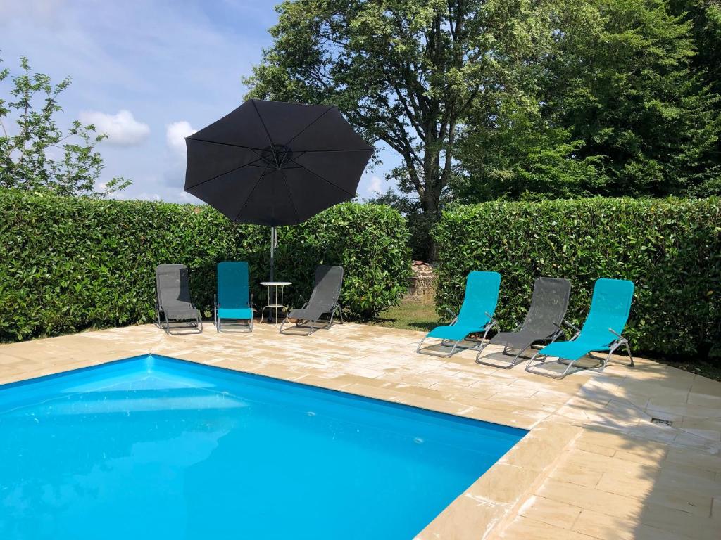 - un groupe de chaises et un parasol à côté de la piscine dans l'établissement Domaine des Volets Jaunes familial avec piscine chauffée - FR-1-586-56, à Préveranges