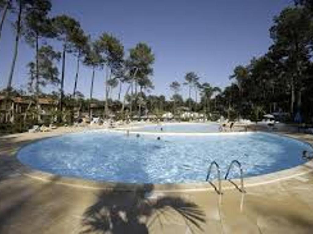 une grande piscine avec des palmiers et des personnes y séjournant dans l'établissement Maison avec piscine - 6 pers - Près de la mer - FR-1-239-1118, à Ondres