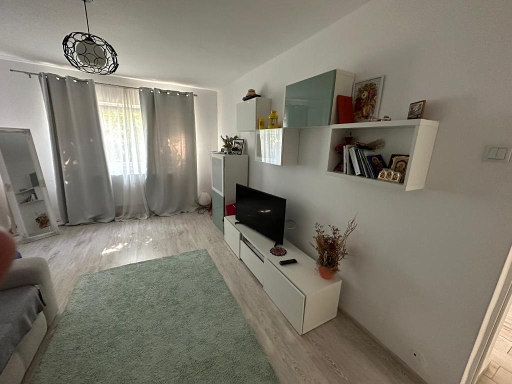 ein weißes Wohnzimmer mit einem TV und einem Sofa in der Unterkunft CMD Apartament 2 camere in Buzău