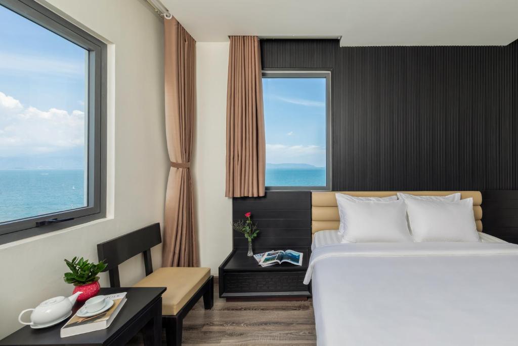 A sea-view bedroom with a double bed, small desk and tea service by the window.