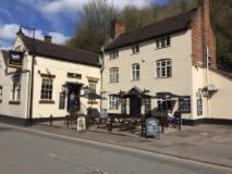 un gran edificio blanco con mesas de picnic delante de él en The Swan Taphouse en Ironbridge