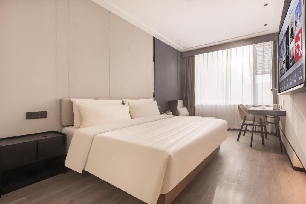 a bedroom with a large white bed and a table at Atour X Hotel Tianjin Binhai Airport Free Trade Zone in Tianjin
