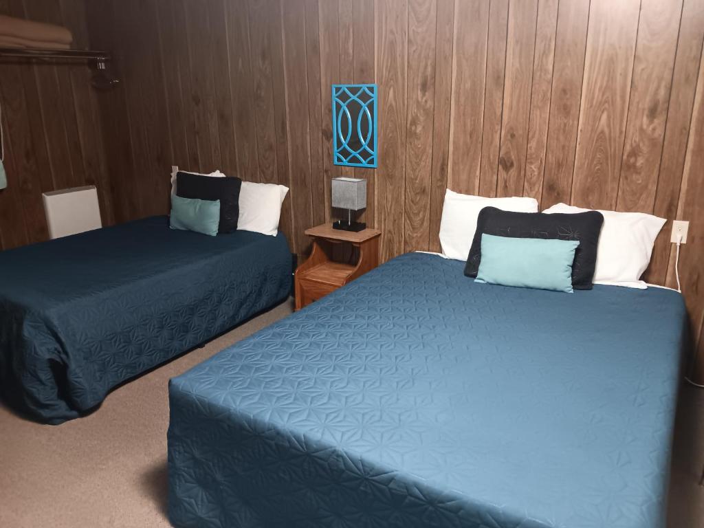 2 letti in camera d'albergo con lenzuola blu di Crawford Motel a Springfield
