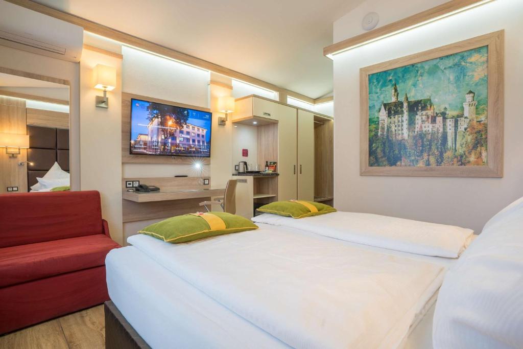 ein Hotelzimmer mit zwei Betten und einer roten Couch in der Unterkunft Best Western Plus Hotel Füssen in Füssen