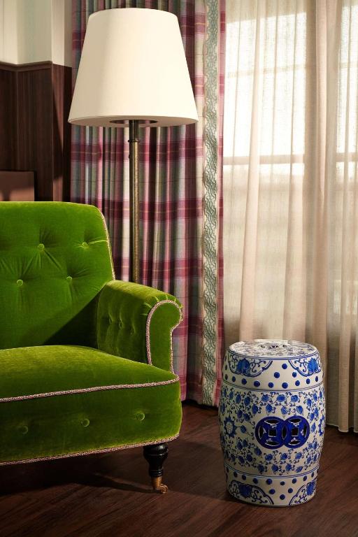 a living room with a green chair and a lamp at Graduate by Hilton Cambridge in Cambridge