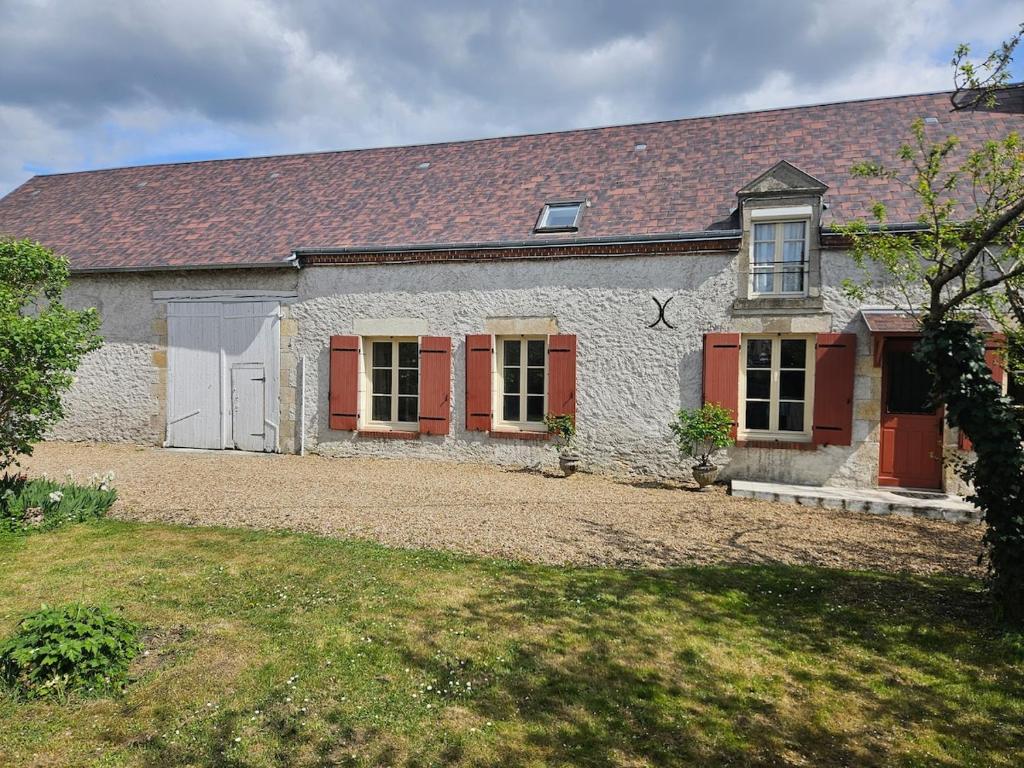 une vieille maison en pierre avec des portes rouges et une cour dans l'établissement La longère de Fabien, à Saint-Jean-de-Braye