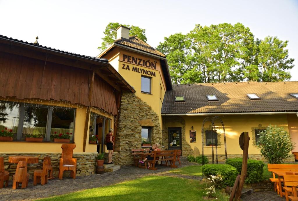 a building with tables and chairs in front of it at Penzion za mlynom in Bešeňová