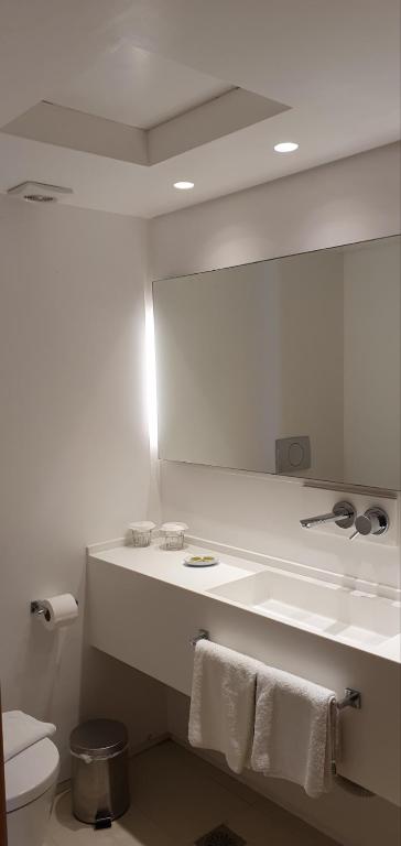 a bathroom with a mirror and a toilet with towels at Spetses Hotel in Spetses