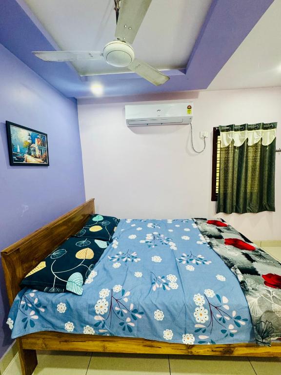 a bedroom with a bed with a blue comforter at Sri padha vallabha serenity homestay in Pithāpuram