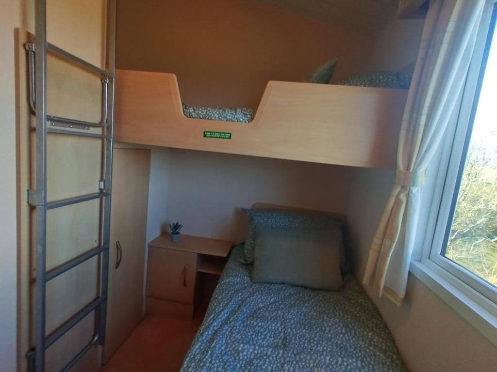 a small bedroom with bunk beds and a desk at Seaside chalet in Ardmore with breathtaking views in Ardmore