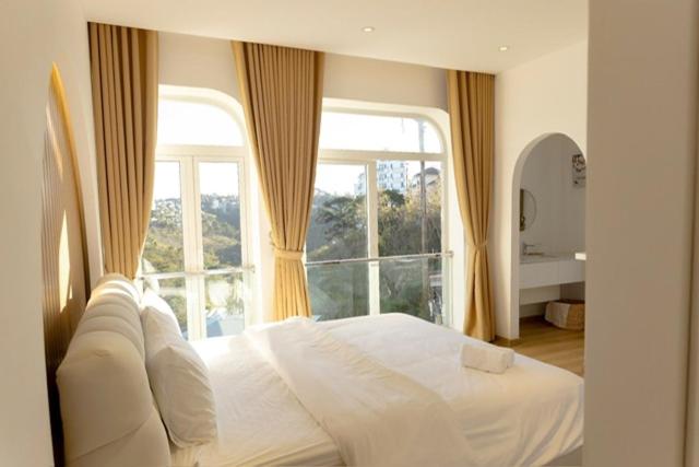 a bedroom with a white bed with a large window at Our Home in Da Lat