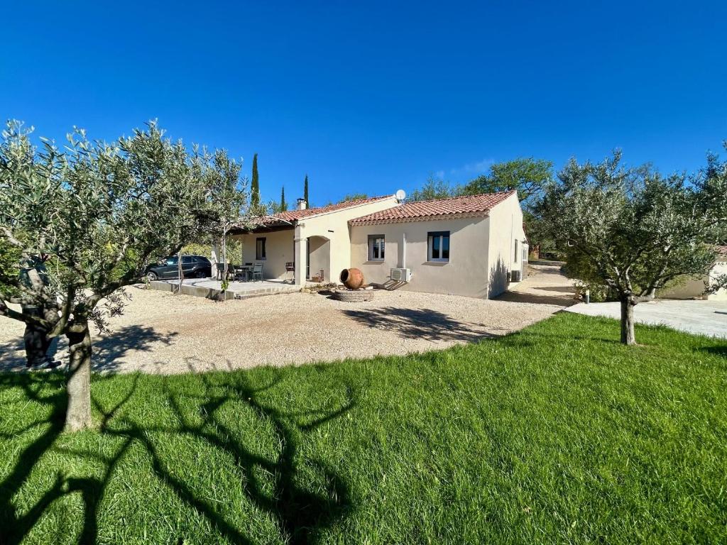 une maison avec des arbres devant une cour dans l'établissement Villa les Oliviers, à Bédoin