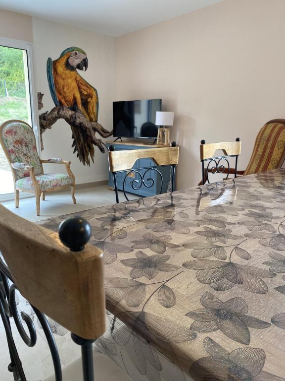 une salle à manger avec une table et un perroquet assis sur une branche dans l'établissement Gite le Perroquet, à Seigy