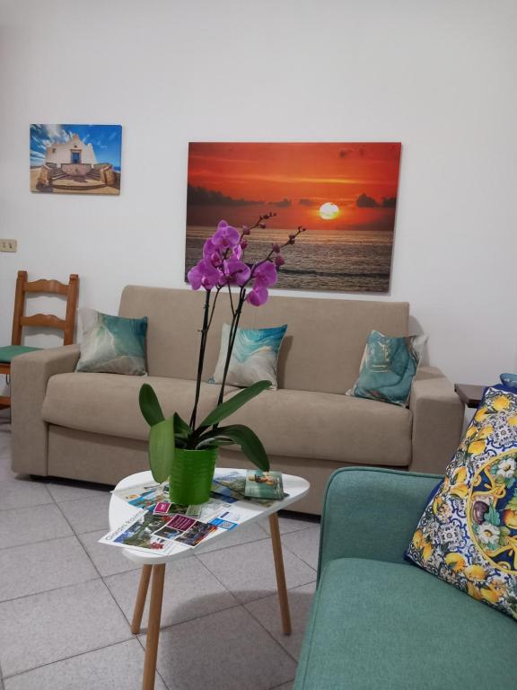 a living room with a couch and a table with purple flowers at Appartamento L'Orchidea in Forio d'Ischia
