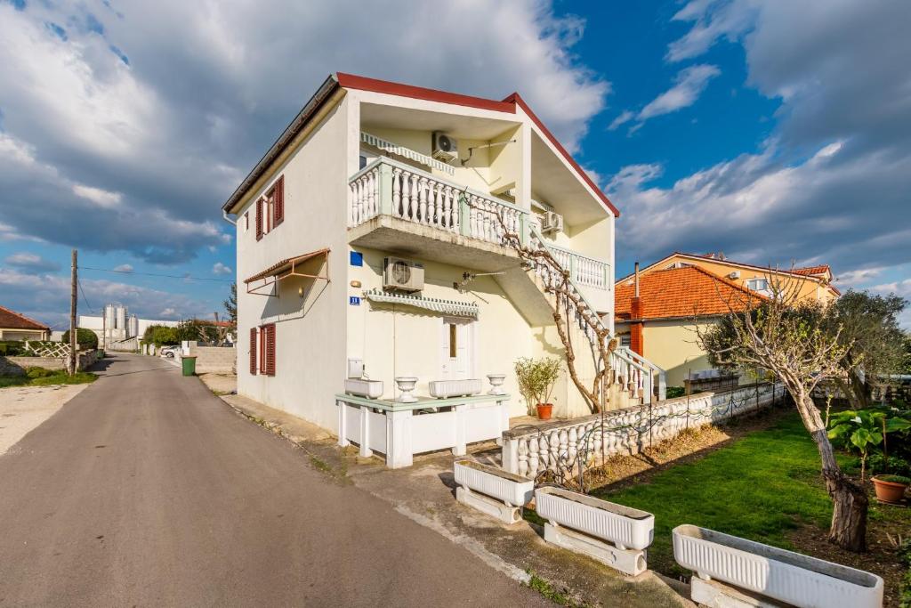 a white building with a balcony on a street at Apartments Papic in Vrsi