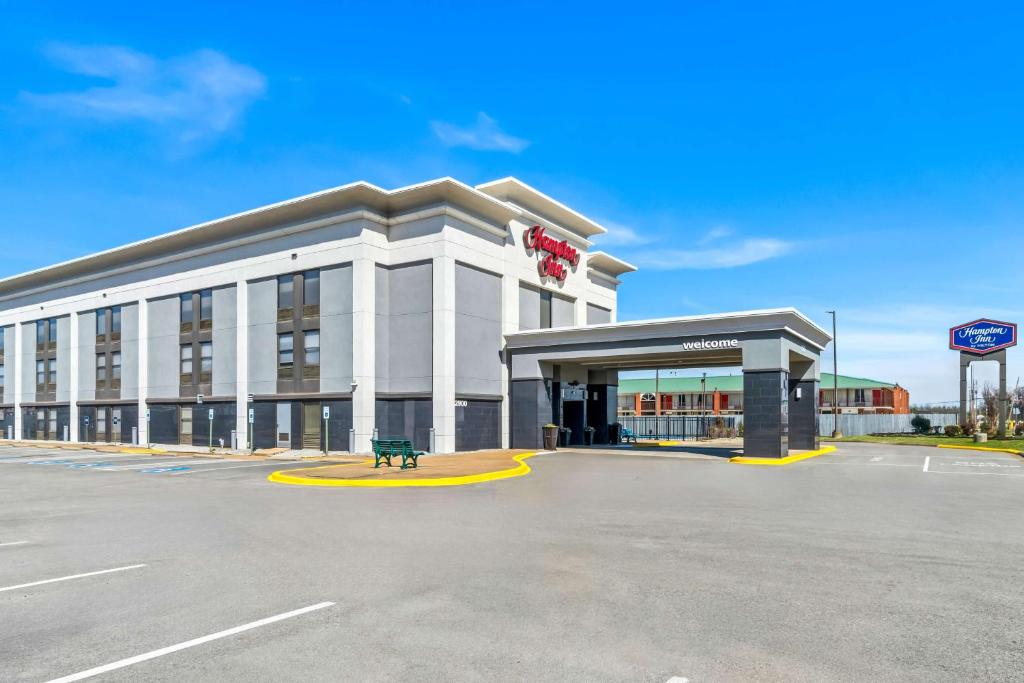 un gran edificio blanco con un banco delante en Hampton Inn Jonesboro, en Jonesboro