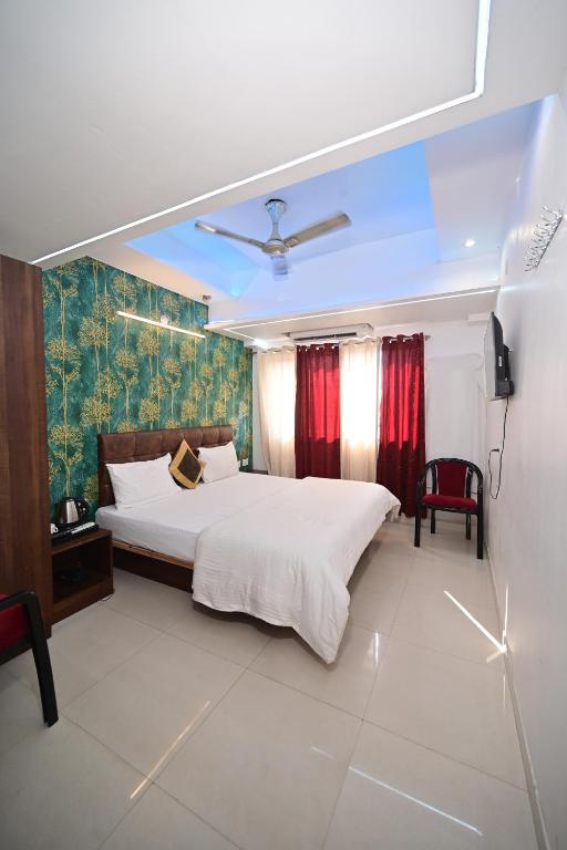 una camera da letto con un grande letto bianco e tende rosse di Hotel Shivansh a Varanasi