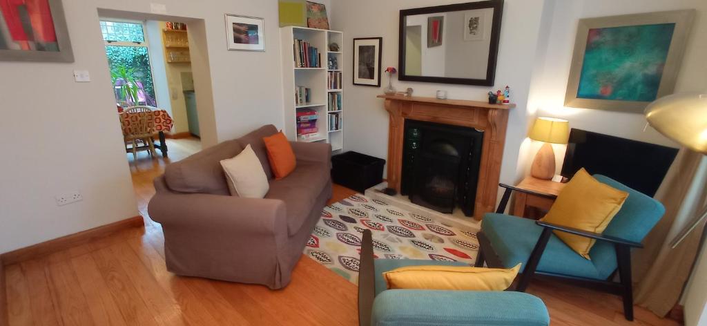een woonkamer met een bank en stoelen en een open haard bij No 14 -A Cosy Townhouse in Westport in Westport