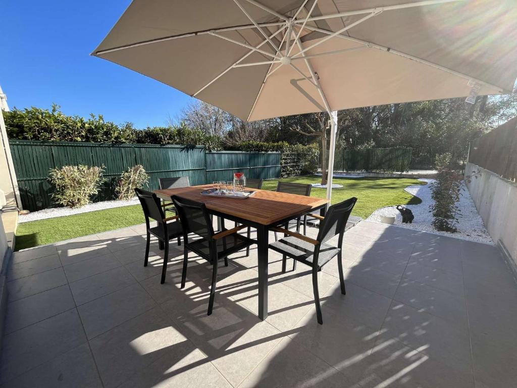 Una mesa y sillas bajo una sombrilla en un patio. en Appartement jardin à deux pas de la mer Classé 3 étoiles, en Poggio-Mezzana