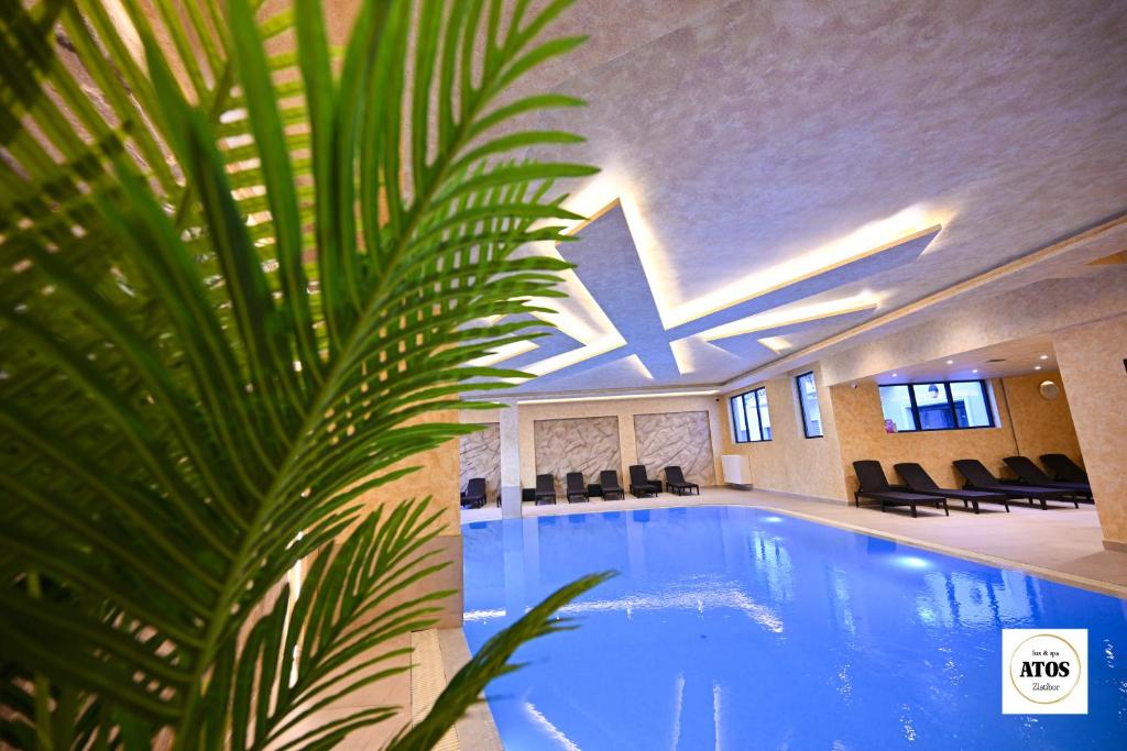 una gran piscina en un edificio con una palmera en Atos lux & spa Zlatibor, en Zlatibor