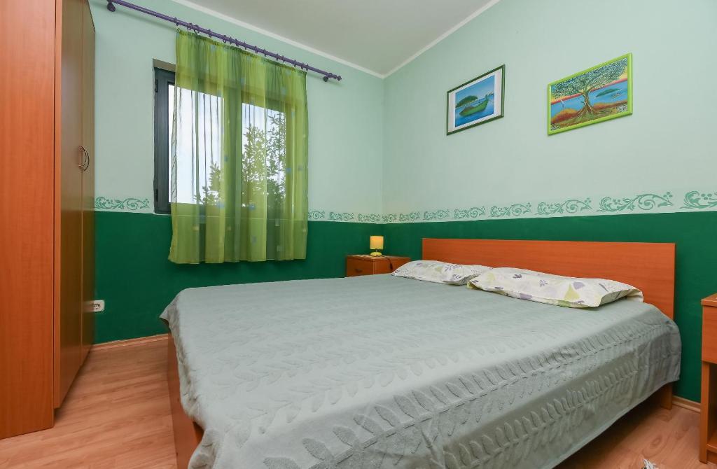 sypialnia z łóżkiem i zieloną ścianą w obiekcie Apartments Toni w mieście Maslinica