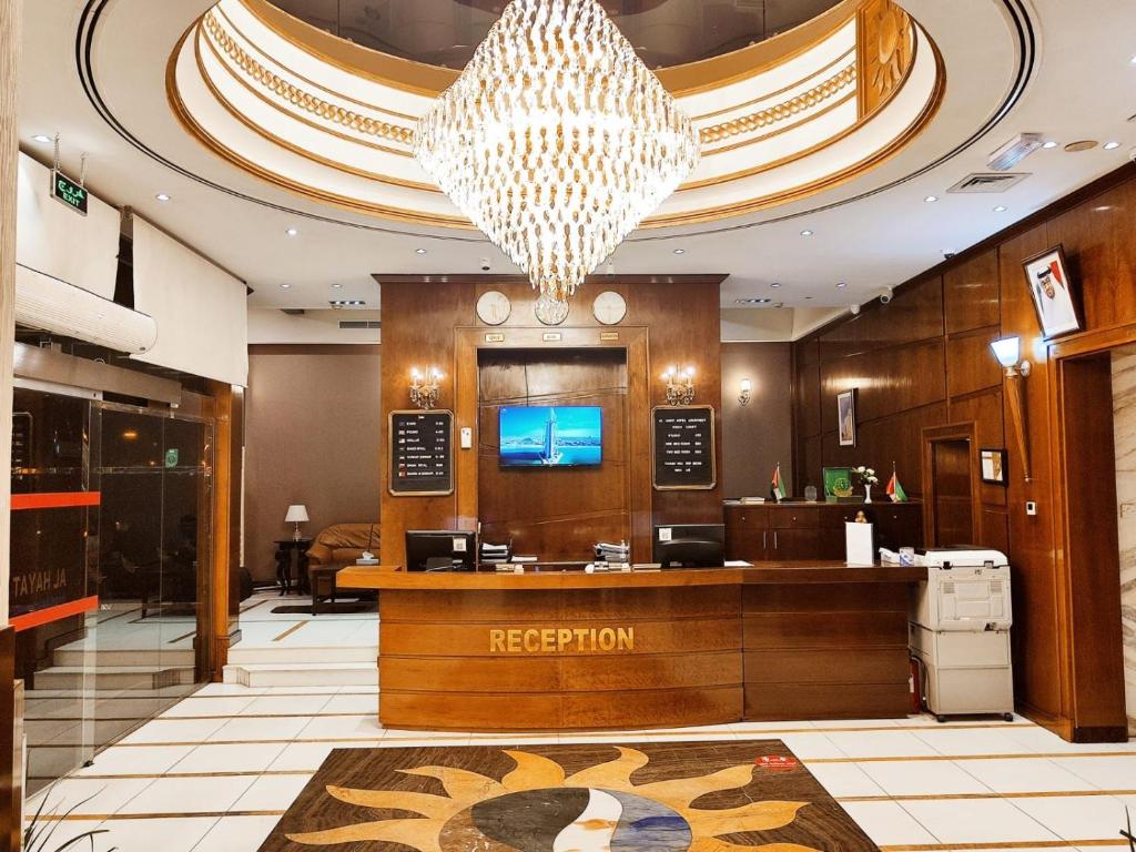 a hotel lobby with a reception desk and a chandelier at Al Hayat Hotel Apartments in Sharjah