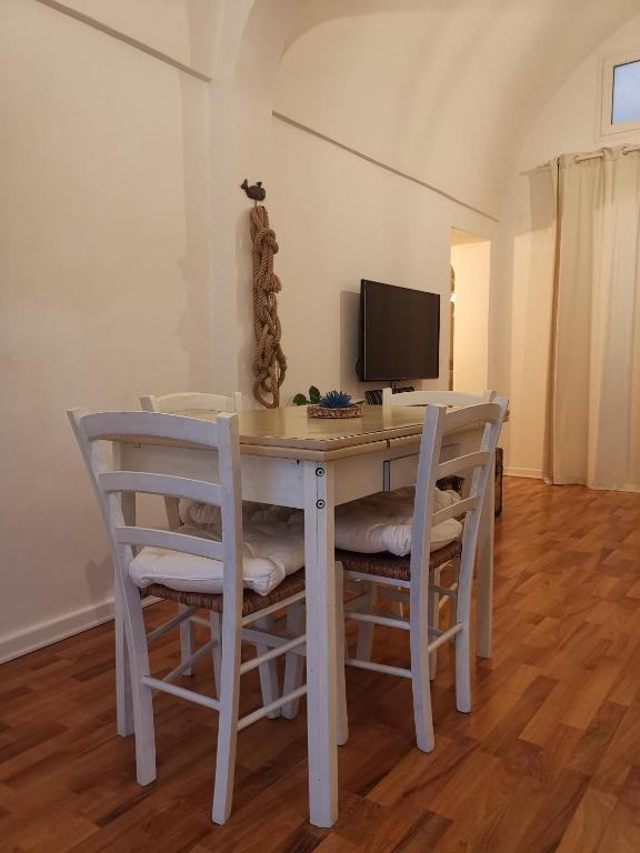 einen weißen Esstisch mit Stühlen und einem TV in der Unterkunft Stella di mare Apartment in Monopoli