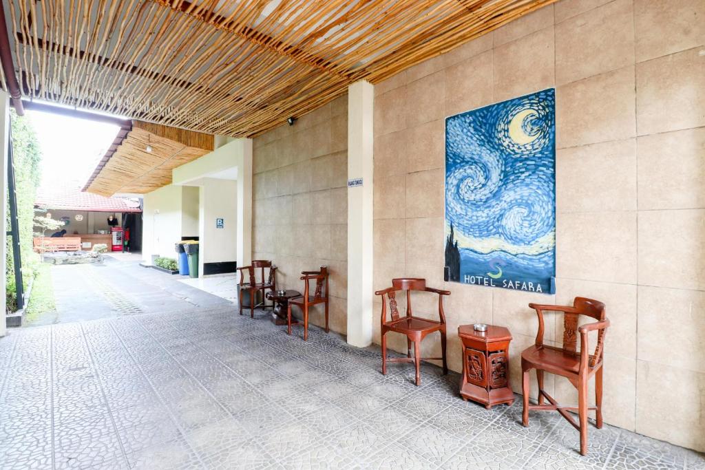 una stanza con sedie e un dipinto sul muro di Hotel Safara Yogyakarta a Yogyakarta