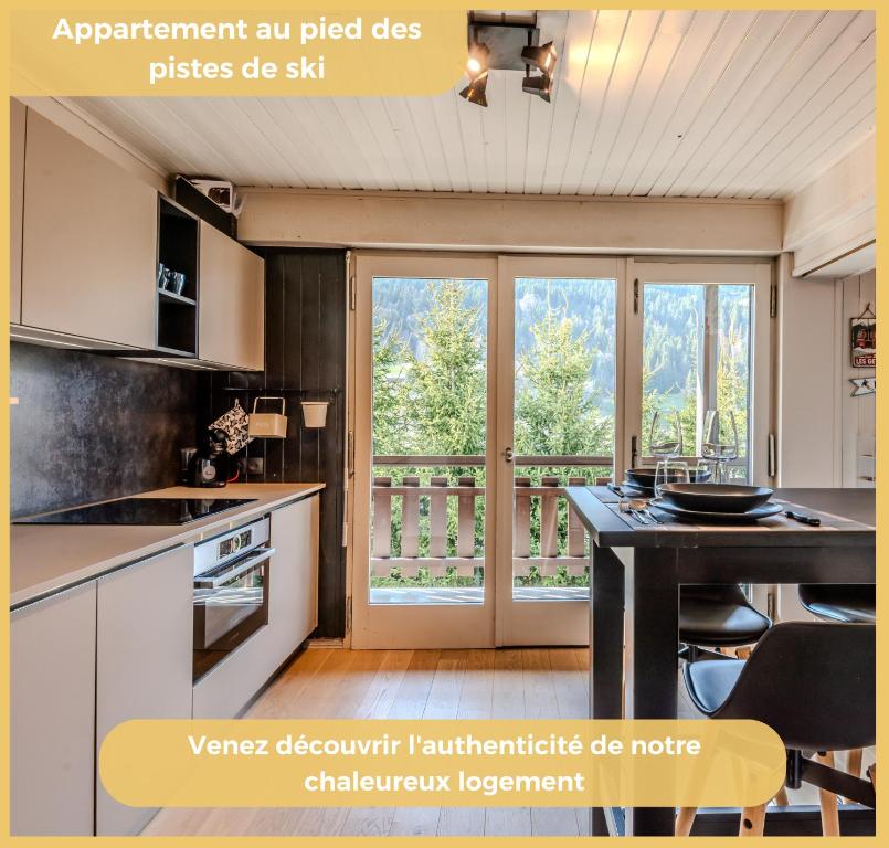 une image d'une cuisine avec une porte coulissante en verre dans l'établissement La Grange Neuve I T1 I Les Gets, aux Gets