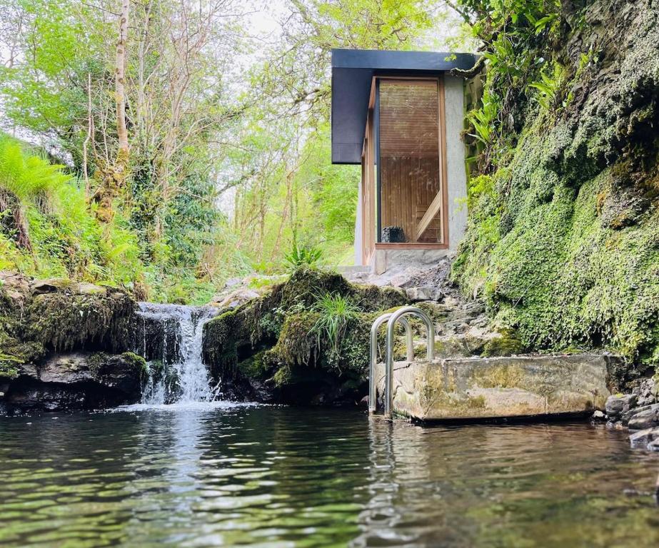 a small house on the side of a river with a waterfall at River Cottage Retreat Hideaway Sauna Sligo Leitrim in Sligo