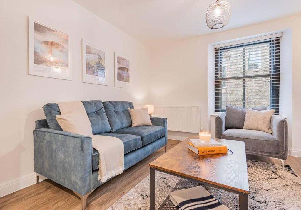 ein Wohnzimmer mit einem blauen Sofa und einem Tisch in der Unterkunft Carpenters Cottage - The Lakes! in Kendal
