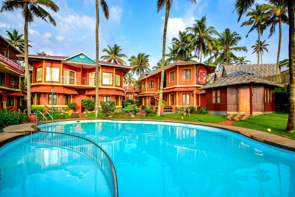 duży basen przed domem z palmami w obiekcie Krishnatheeram Ayur Holy Beach Resorts w mieście Varkala