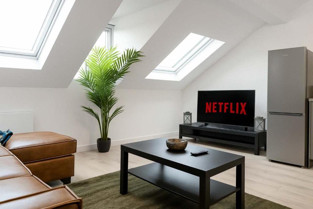 a living room with a couch a table and a tv at Stunning 1 bed Penthouse Apartment in East Village, Belfast - Walk to City Centre, Roof Terrace in Belfast