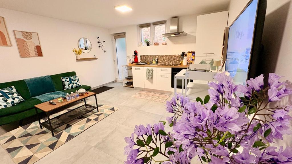 a living room with a green couch and purple flowers at Cocon urbain , bel appartement entièrement équipé, entrée privée, parking in Wittenheim