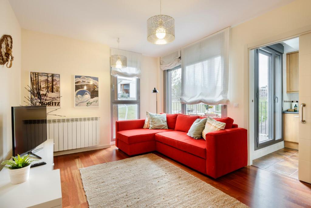 a living room with a red couch and a window at Duplex Las Margas Vistas Montañas in Sabiñánigo
