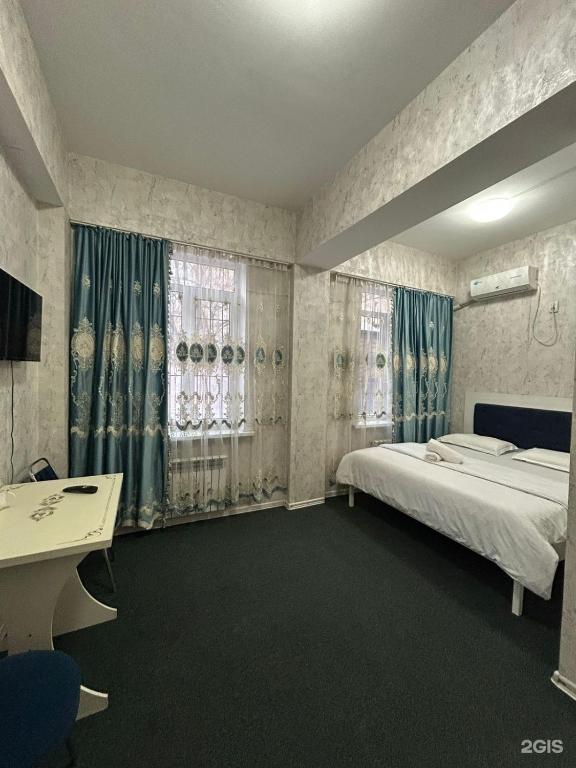 a bedroom with a bed and a desk and windows at Айымхан in Almaty