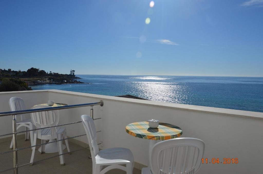 balcón con mesa, sillas y vistas al océano en Mare e Sole Villa Urso en Avola